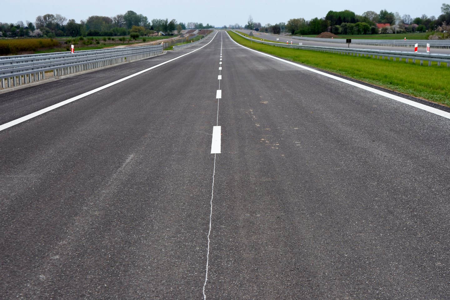 Eine frisch asphaltierte Autobahn erstreckt sich in Richtung ferner Bäume.