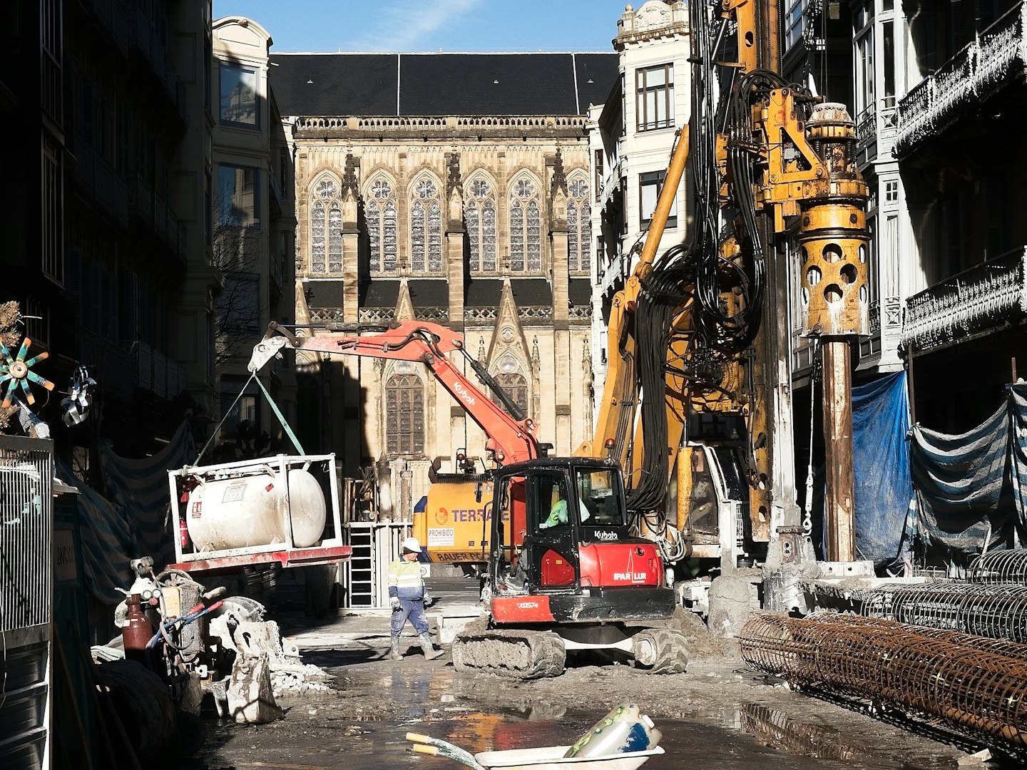 Bauarbeiter beaufsichtigt schwere Maschinen auf einer schlammigen Baustelle in der Stadt.