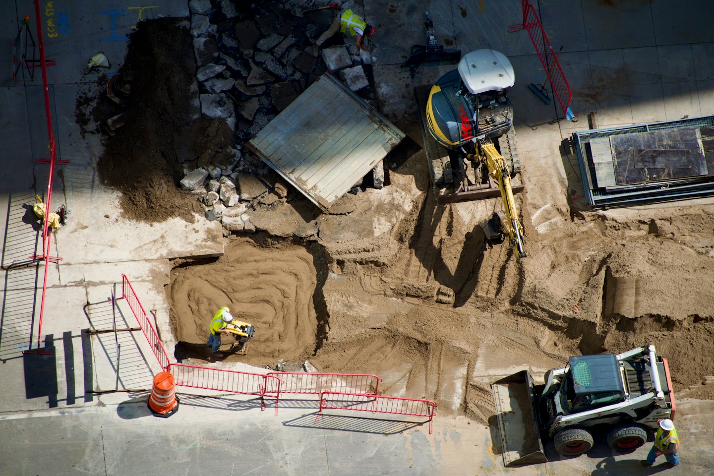 Bauarbeiter bedienen schwere Maschinen auf einer belebten Baustelle.