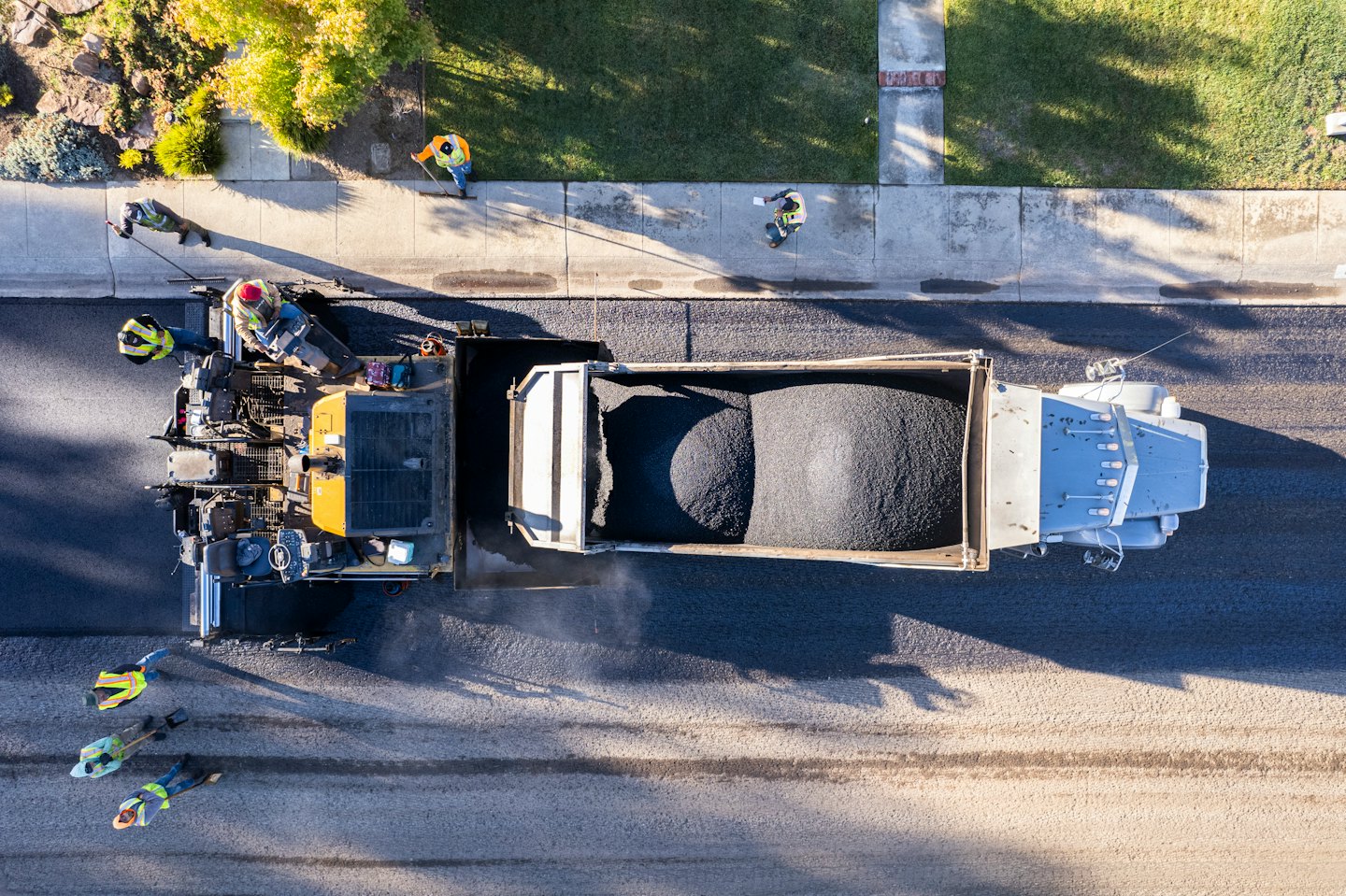 Bauarbeiter legen mit einer Asphaltiermaschine frischen Asphalt.